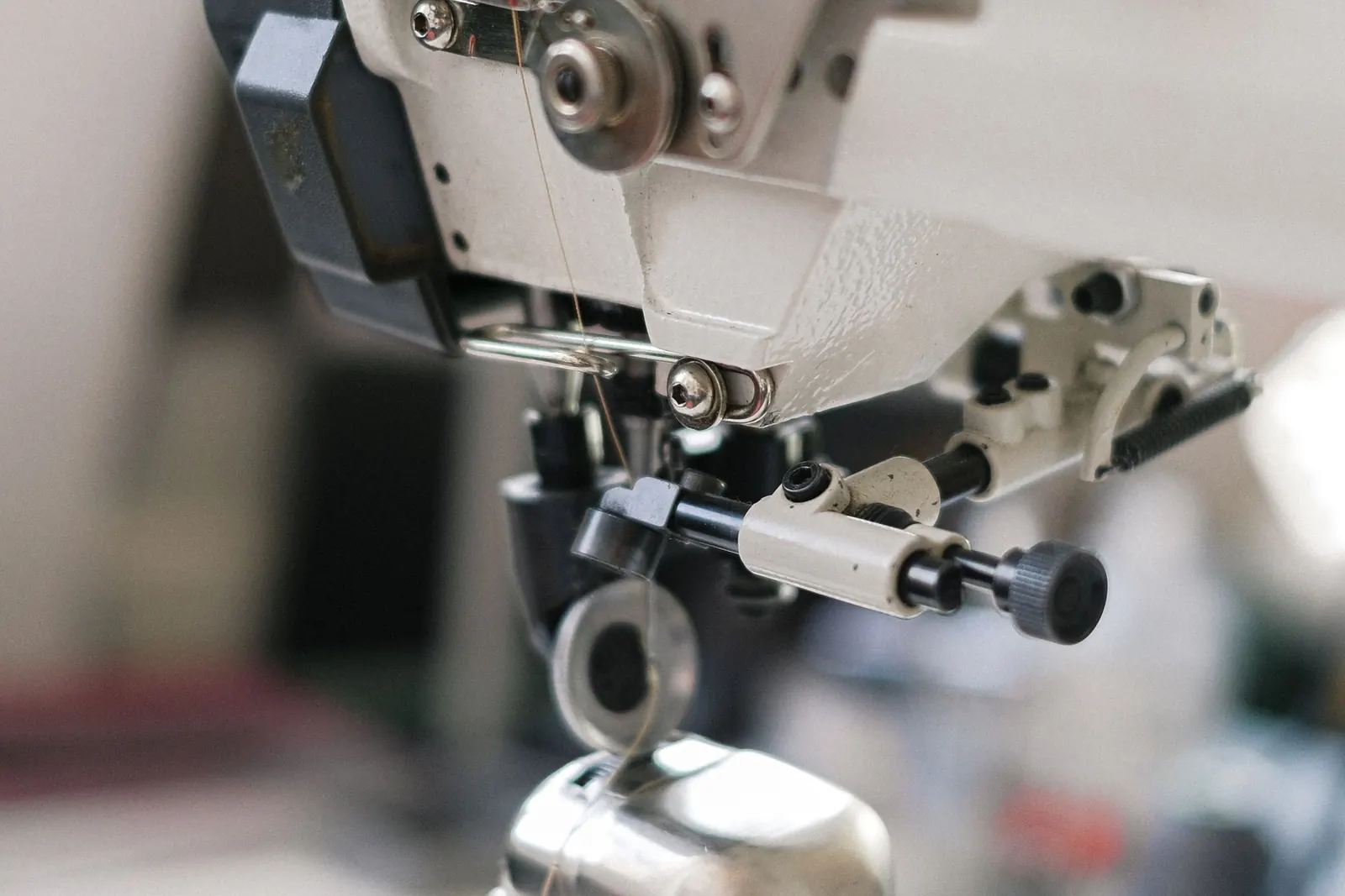 Close-up of an industrial sewing machine needle and presser foot mid-stitch